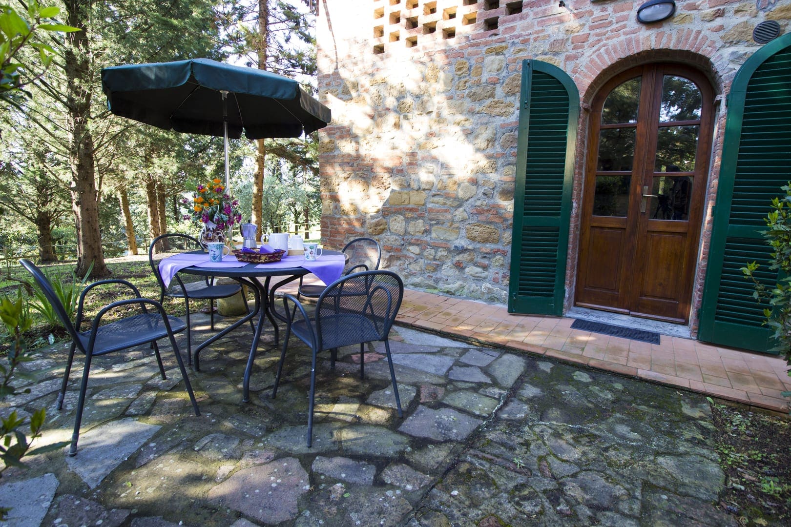 A table and chairs outside of a stone house.