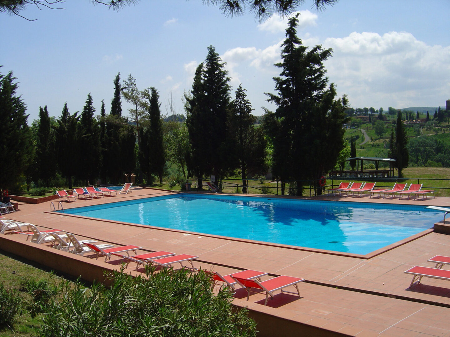 A pool with red chairs and trees in the background