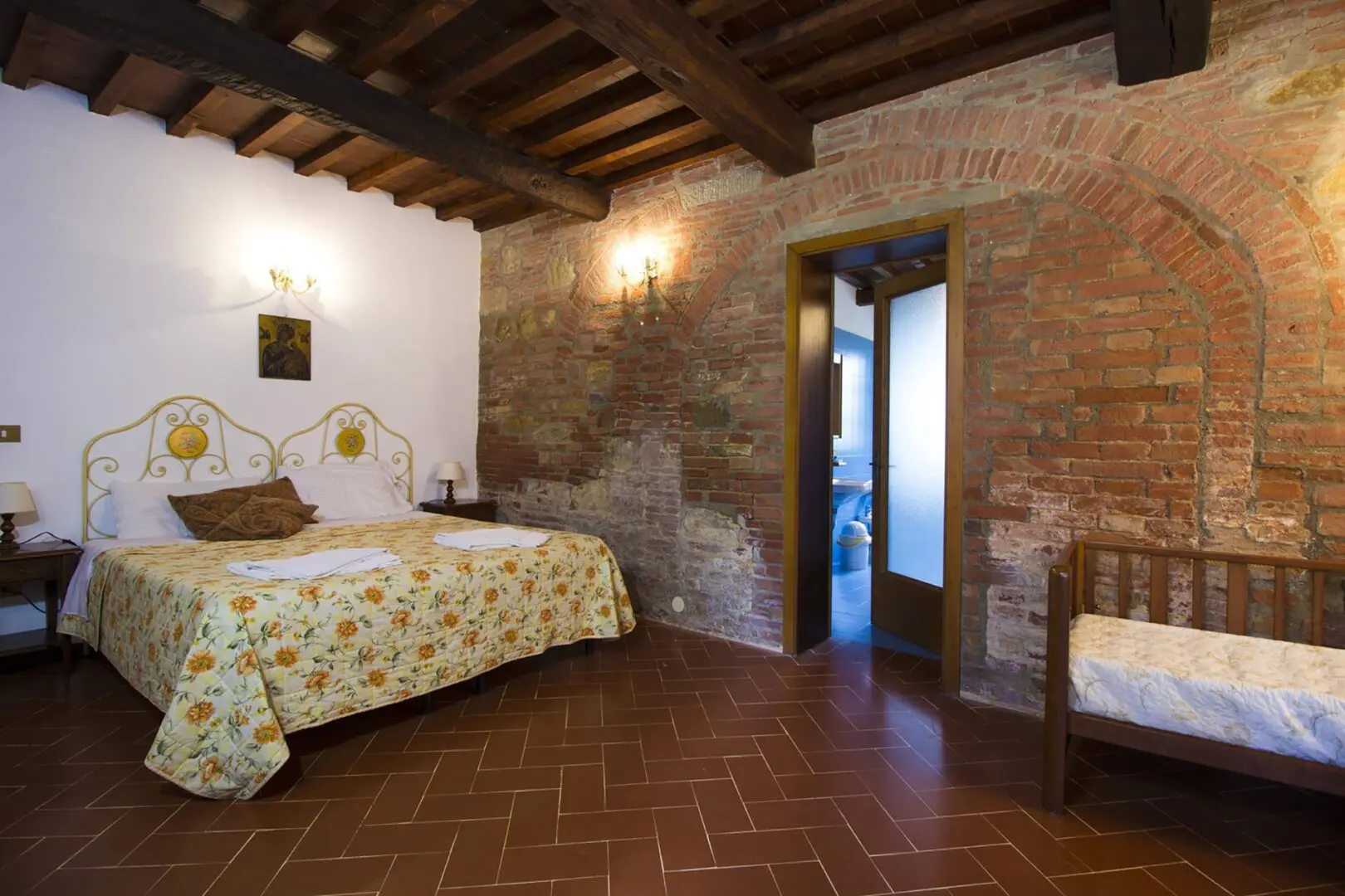 A bedroom with brick walls and wooden floors.