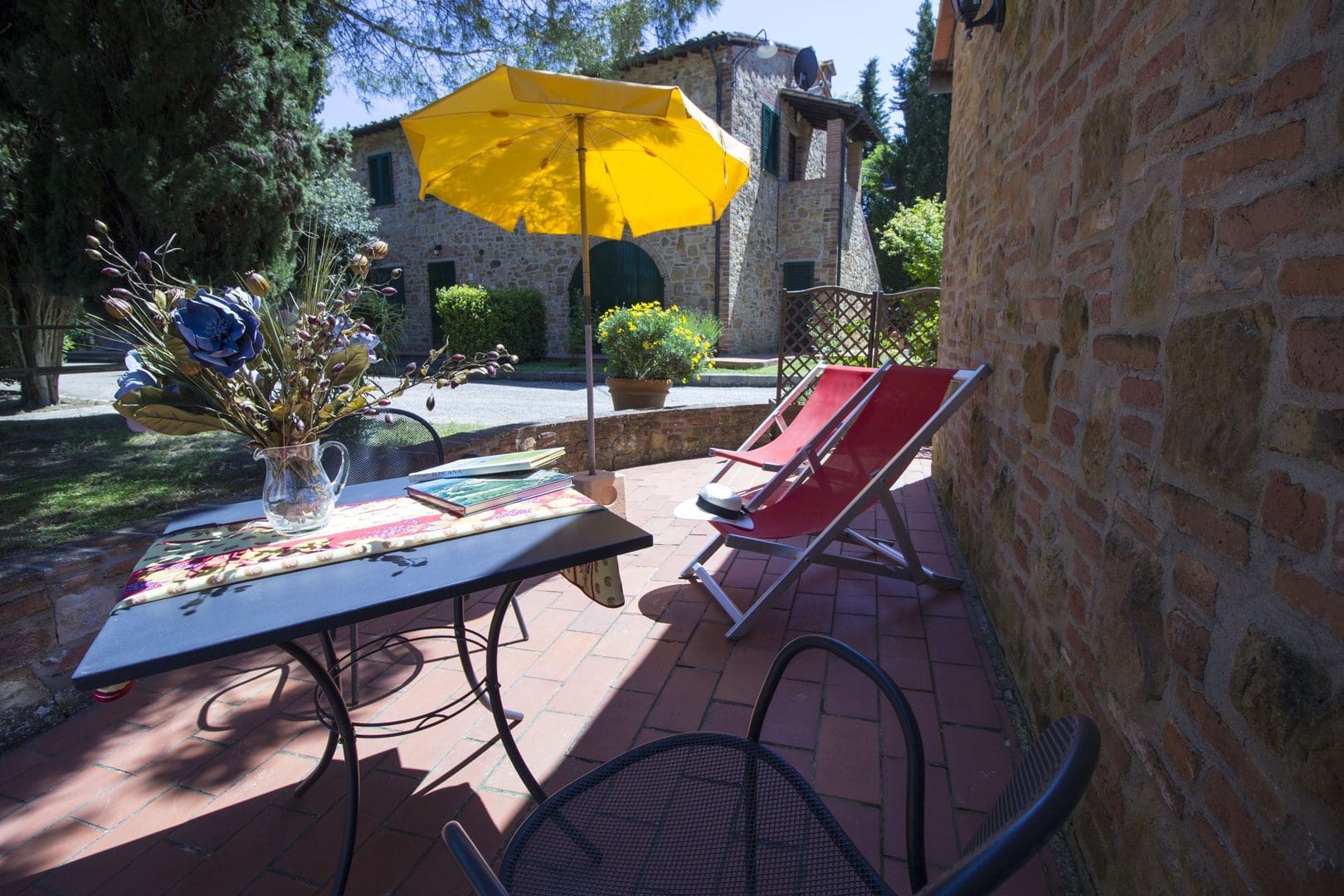 A patio with an umbrella and chairs on the side.