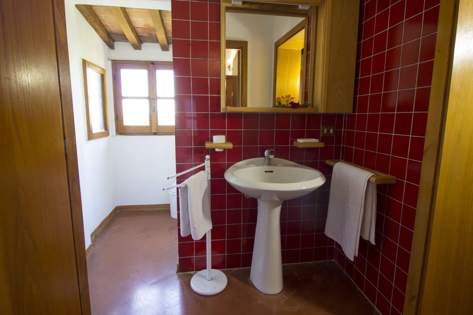 A bathroom with red tile and white fixtures.
