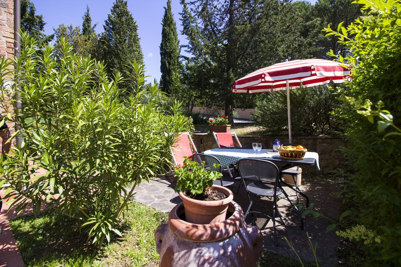 A patio with an umbrella and chairs in the background.