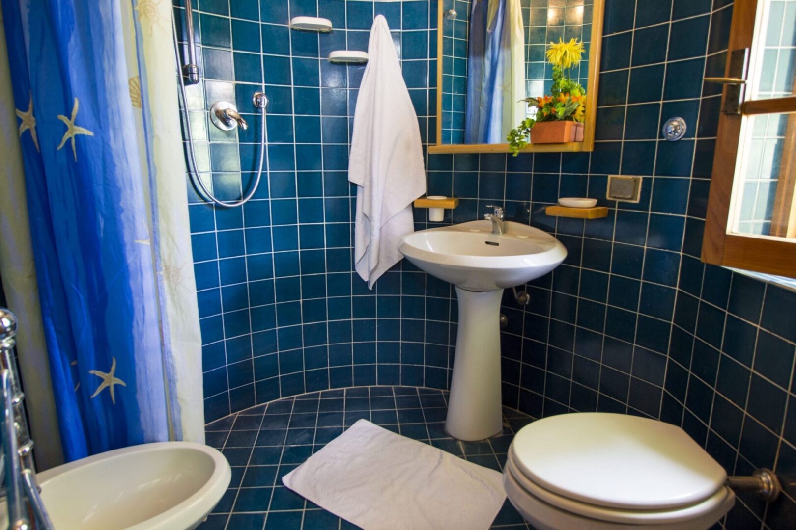 A bathroom with blue tile and white fixtures.