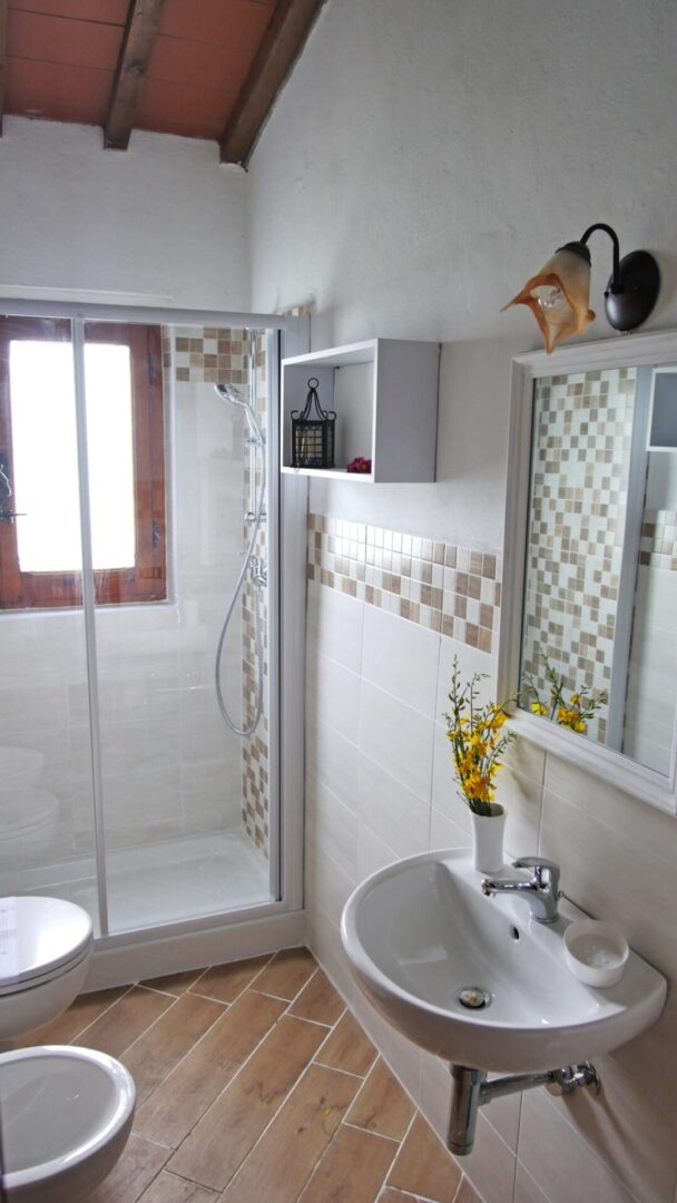 A bathroom with a sink, mirror and shower.