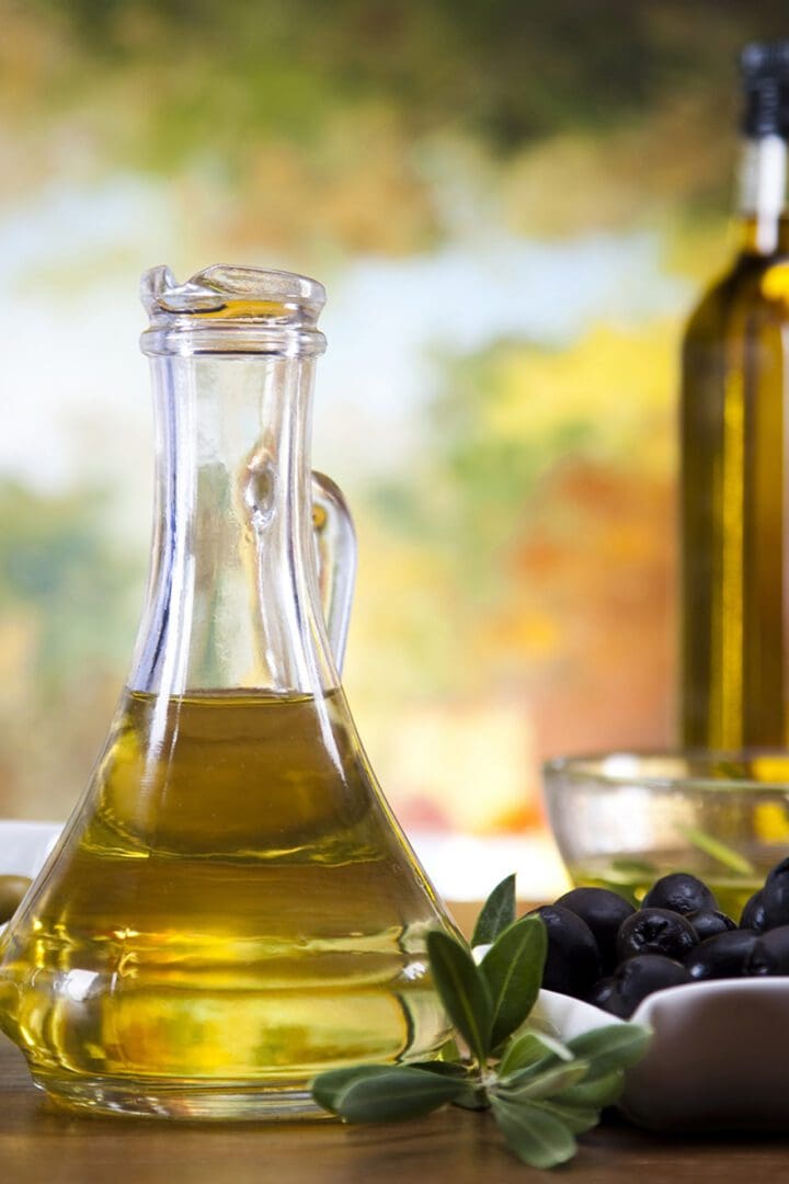 A glass bottle of olive oil sitting on top of a table.