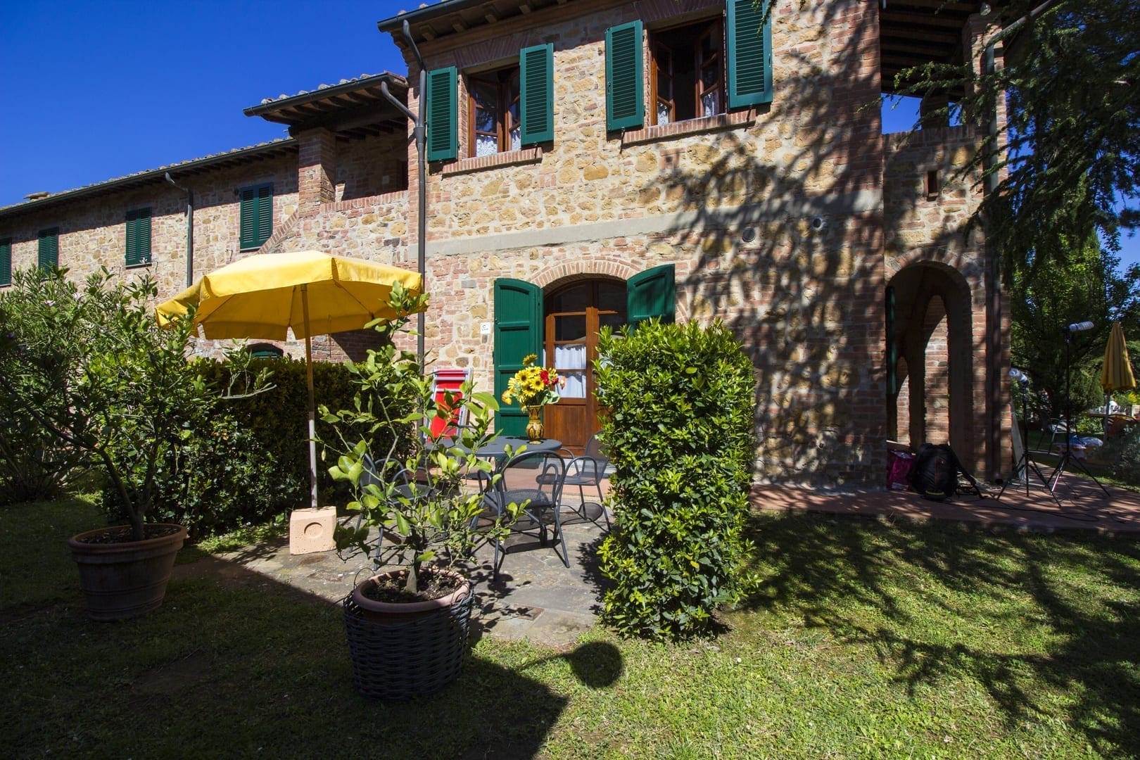 A large stone house with yellow umbrella and green shutters.