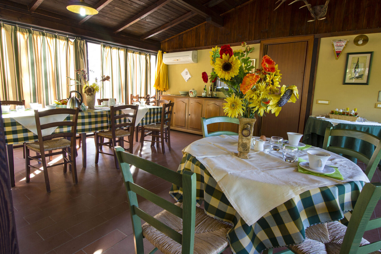 A dining room with tables and chairs, sunflowers in vases.