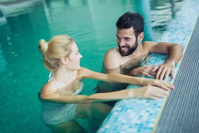 A man and woman in the pool playing on an electronic keyboard.