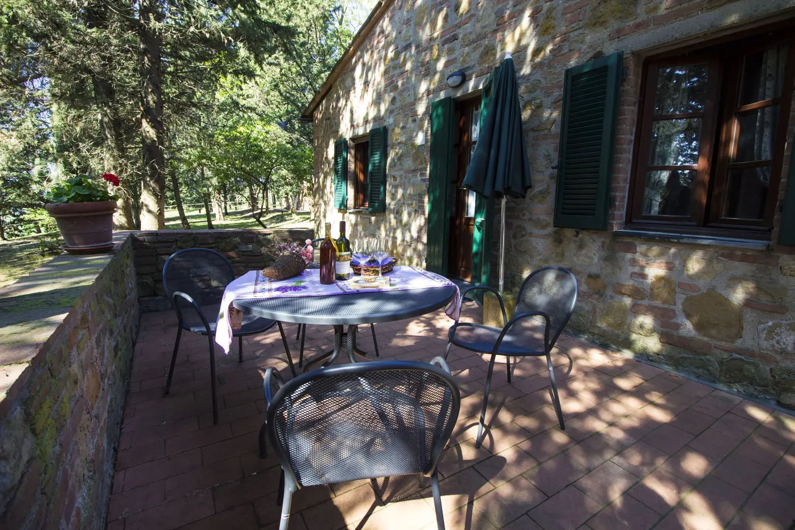 A table and chairs on the patio of an old stone house.