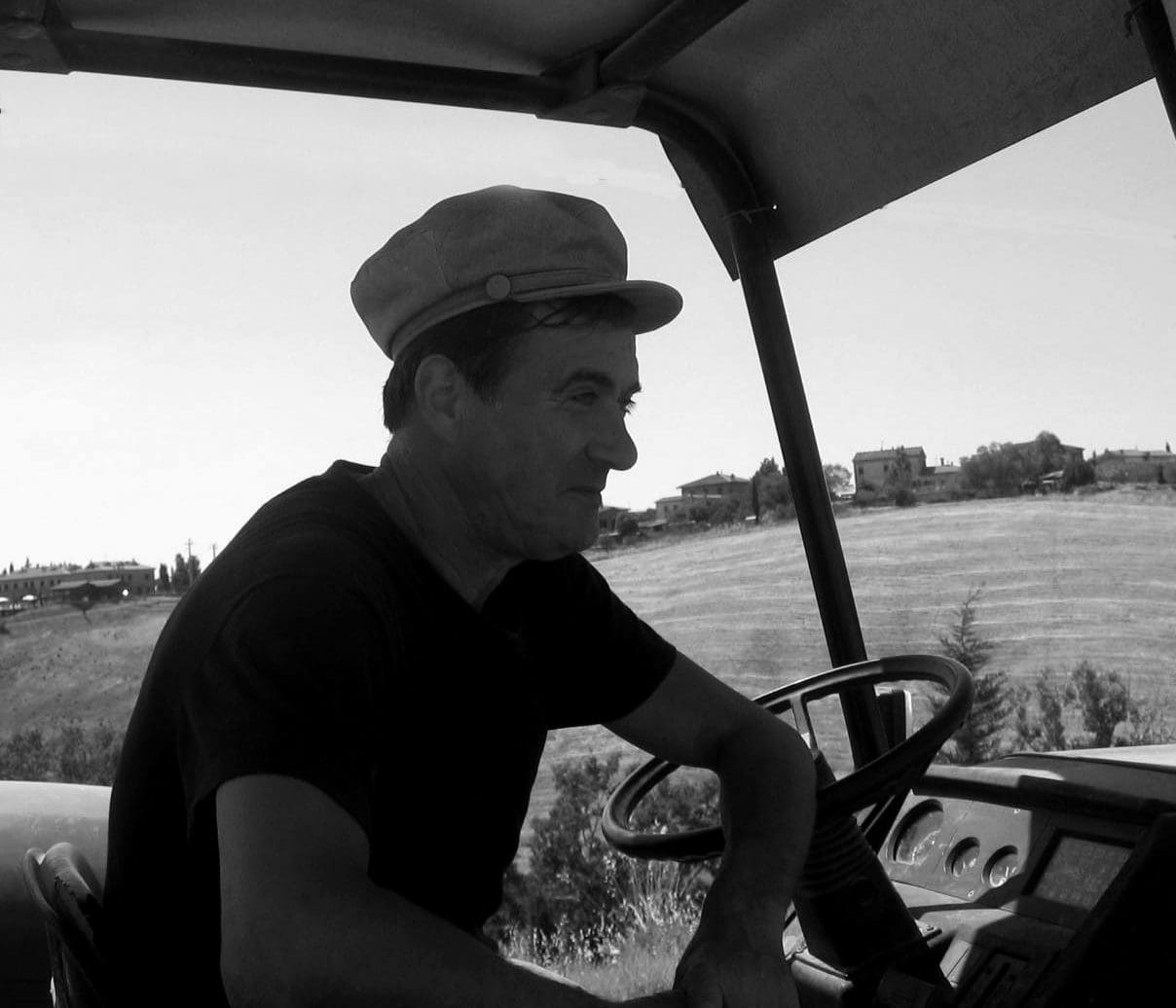 A man driving an old golf cart in the grass.