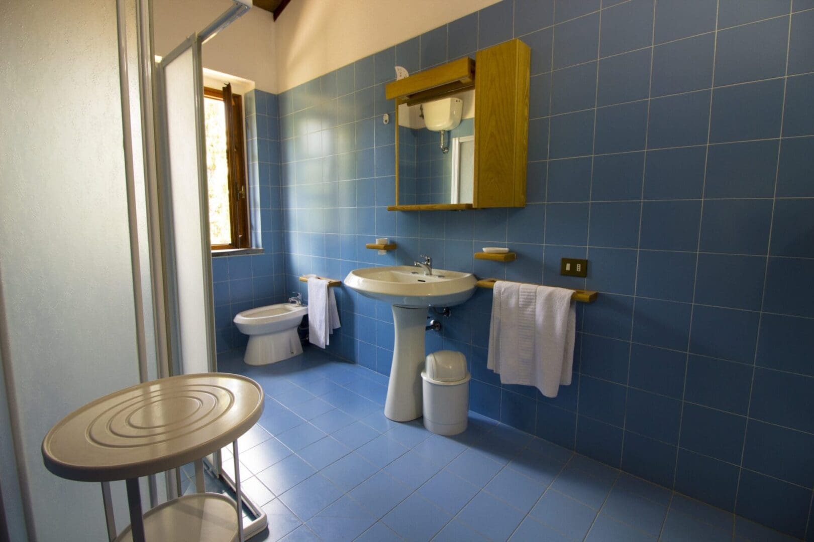 A bathroom with blue tile and white fixtures.