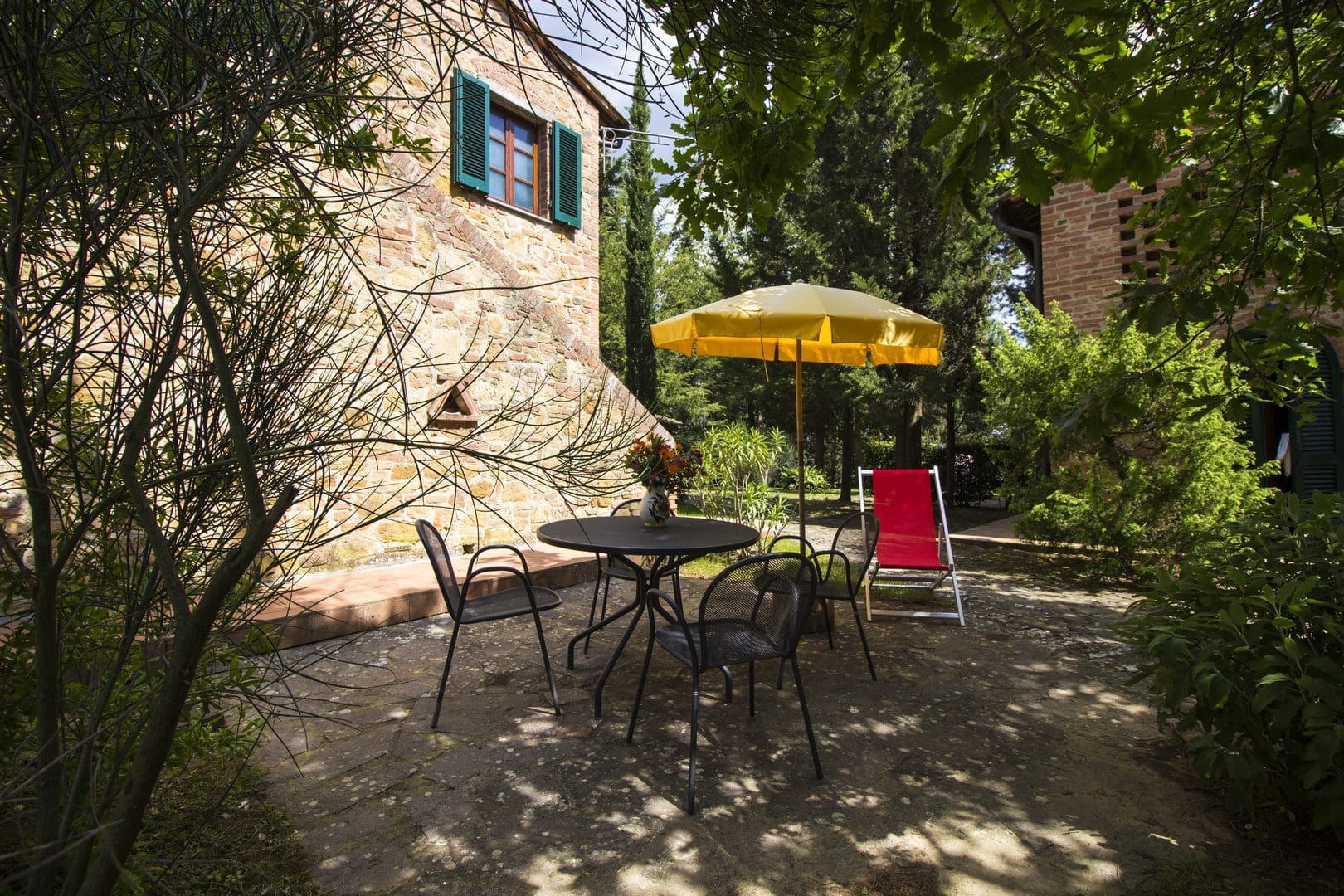 A patio with an umbrella and chairs outside