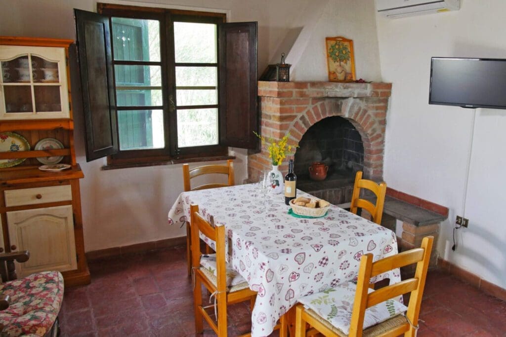 A table with four chairs and a fireplace in the corner.